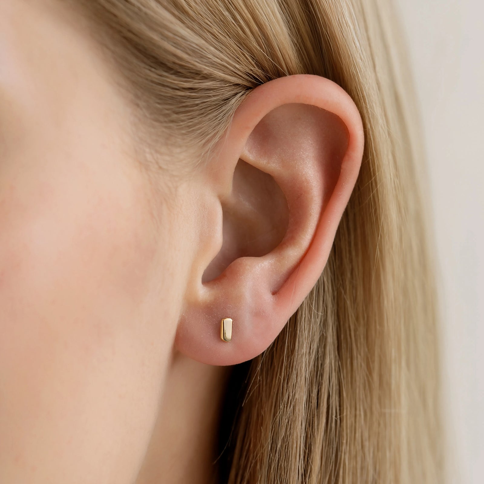 9 ct gold bar studs in a models ear 