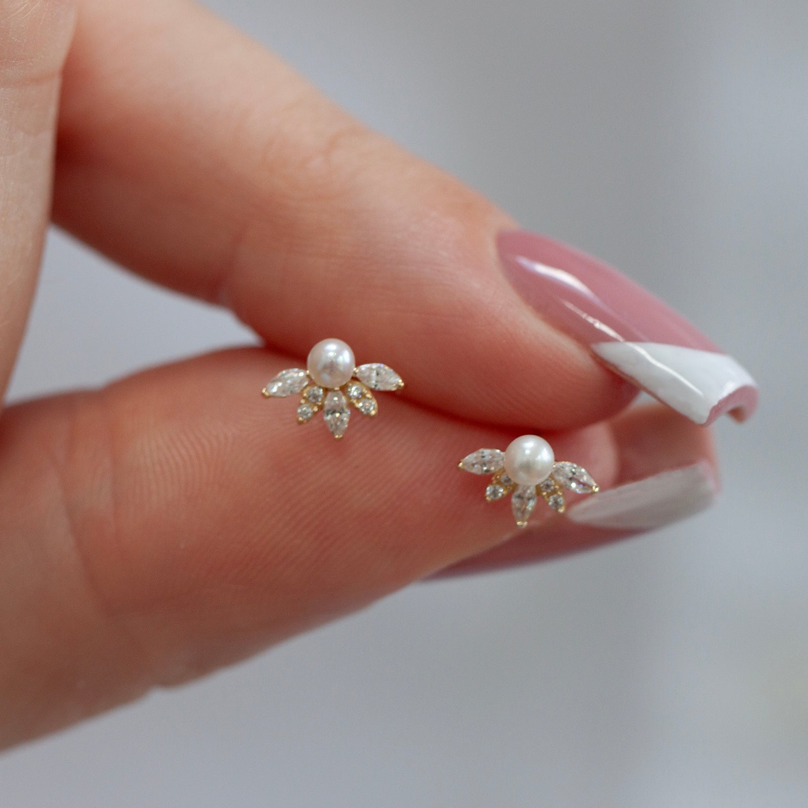 9ct gold pearl and crystal studs in a models hand 