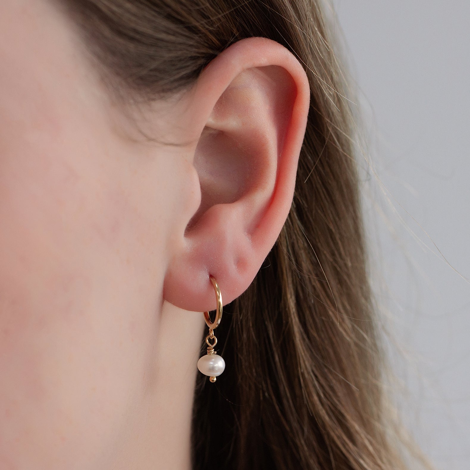 kate freshwater pearl hoop earrings gold in an ear 