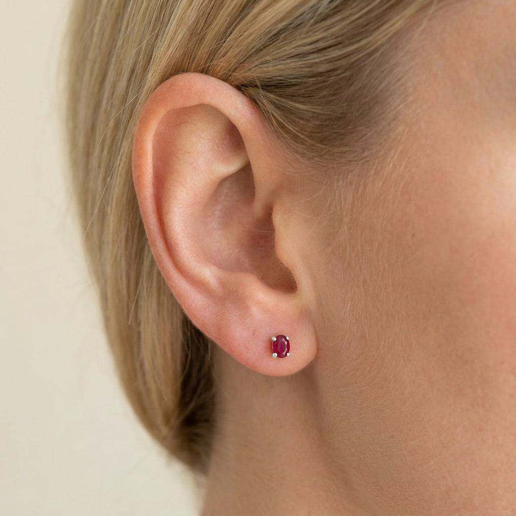 ruby birthstone studs in silver on a models ear 