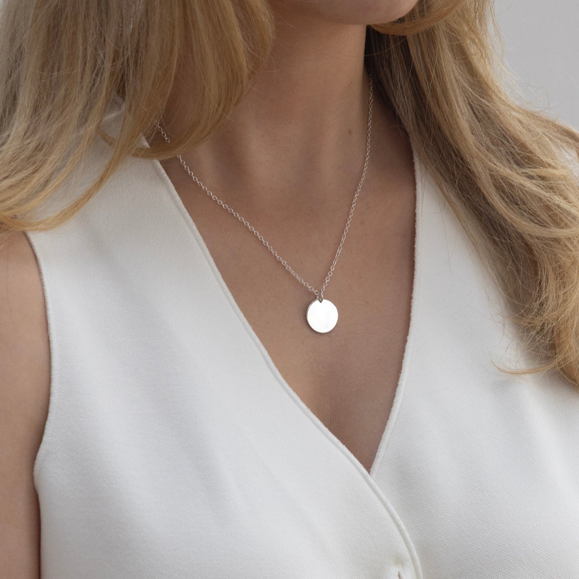 A plain sterling silver disc worn on the neck to show the size and scale of the pendant.