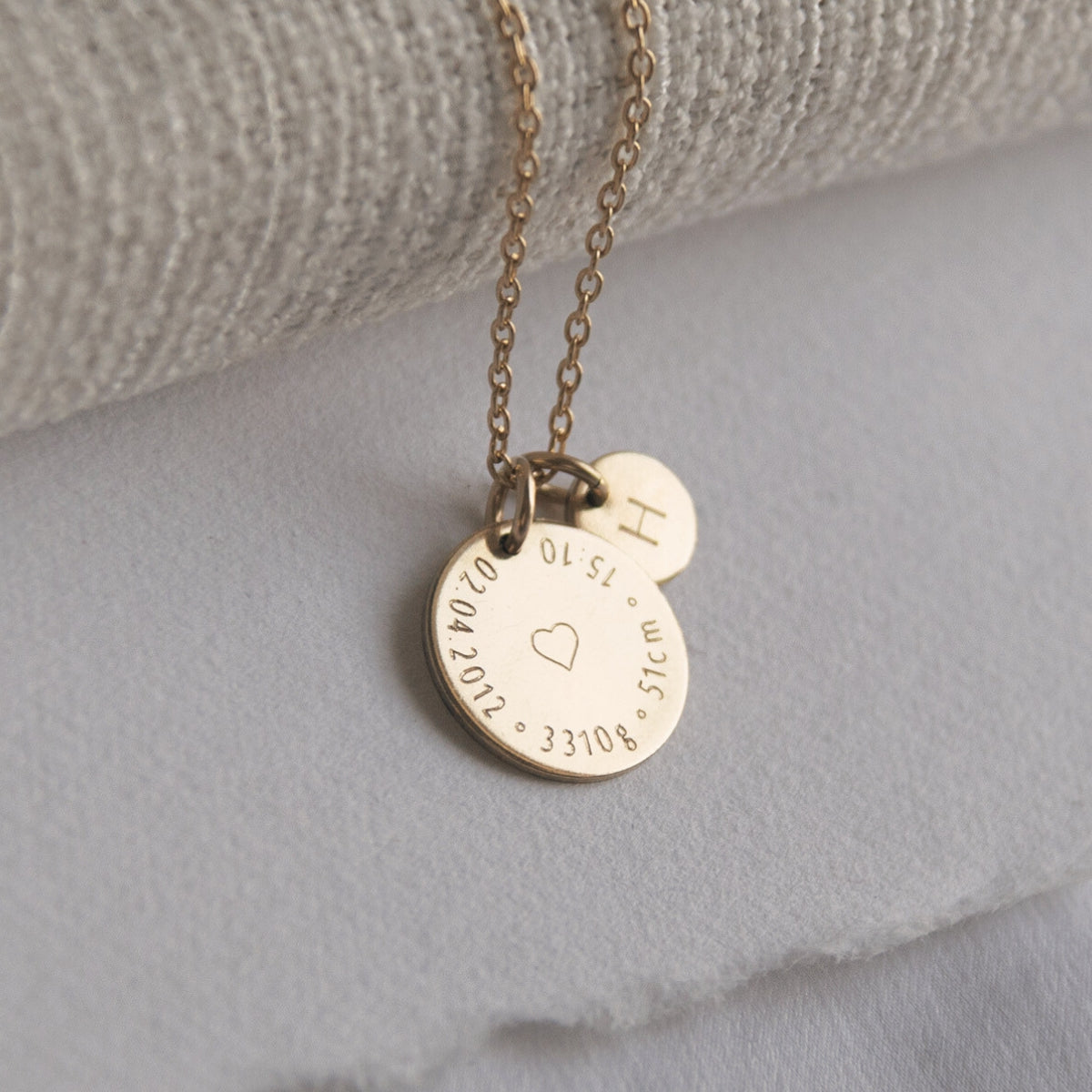Close-up of Birthcoin necklace engraved with baby’s birth date, time, weight and height – custom birth keepsake necklace.