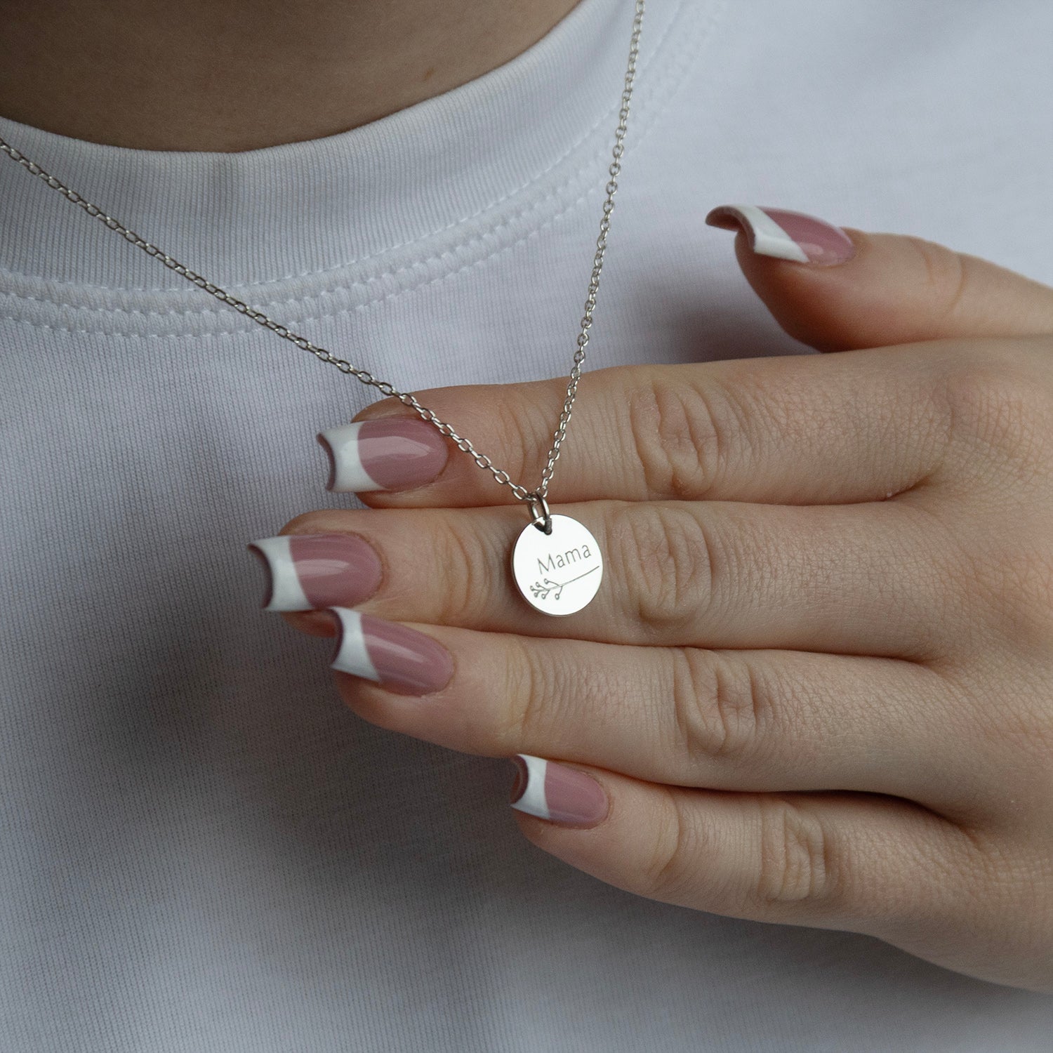 silver botanical mama necklace in a models hand 