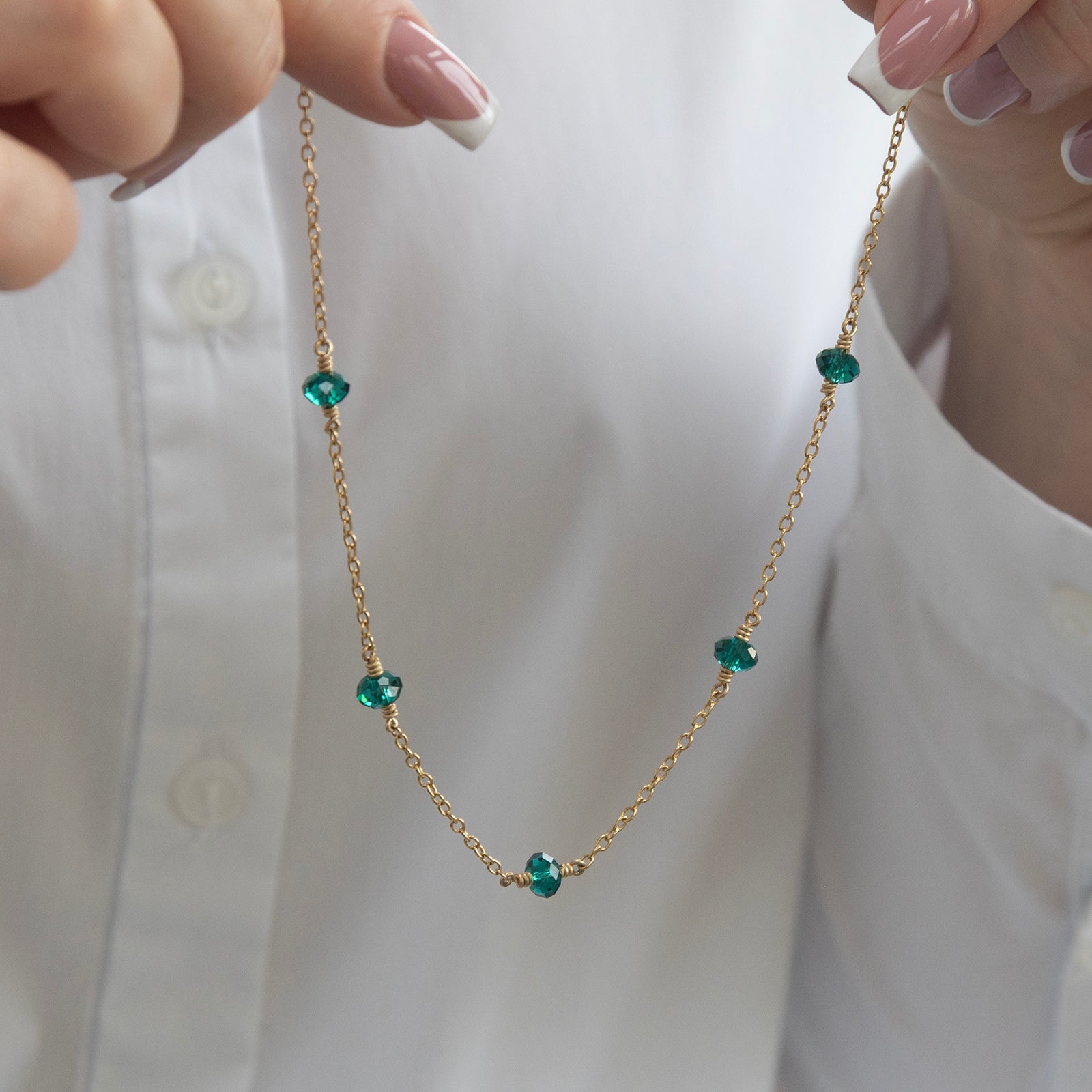 family birthstone necklace with five birthstones in a models hand 