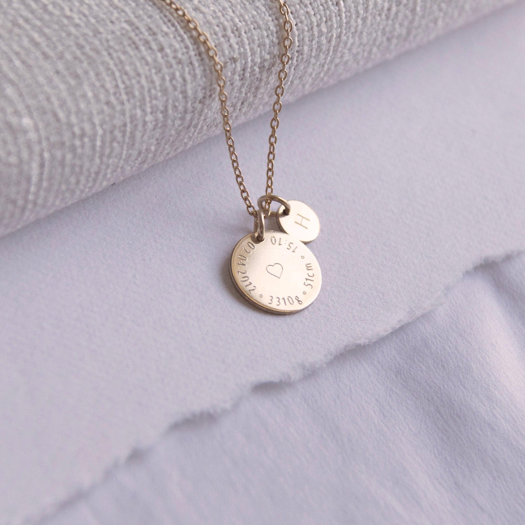 Close-up of Birthcoin necklace engraved with baby’s birth date, time, weight and height – custom birth keepsake necklace.