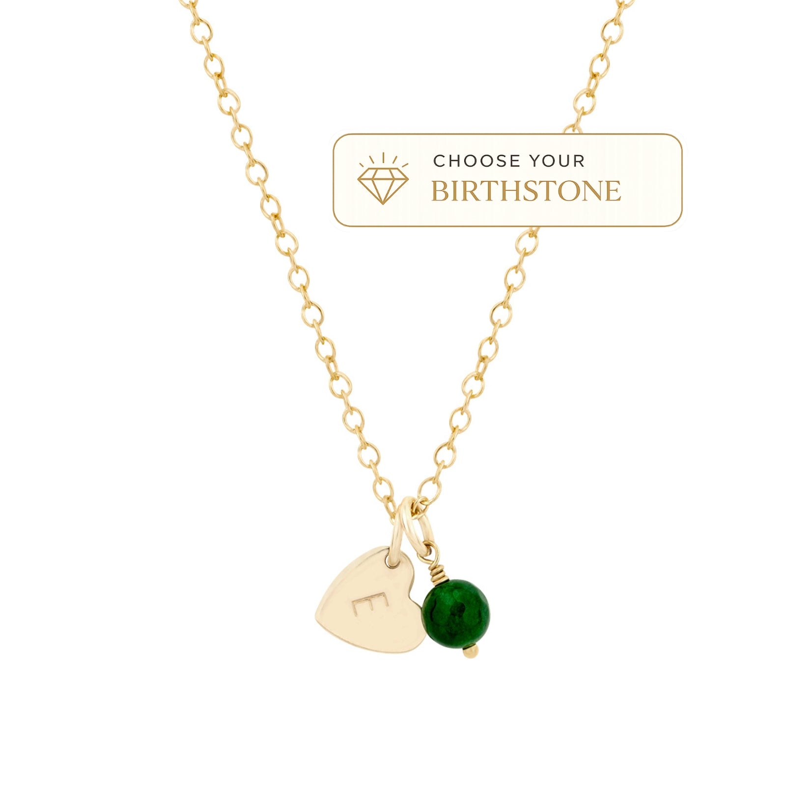 A gold chain necklace with a heart-shaped pendant engraved with a letter and a small green round bead charm, shown on a white background with a 'Choose Your Birthstone' label.