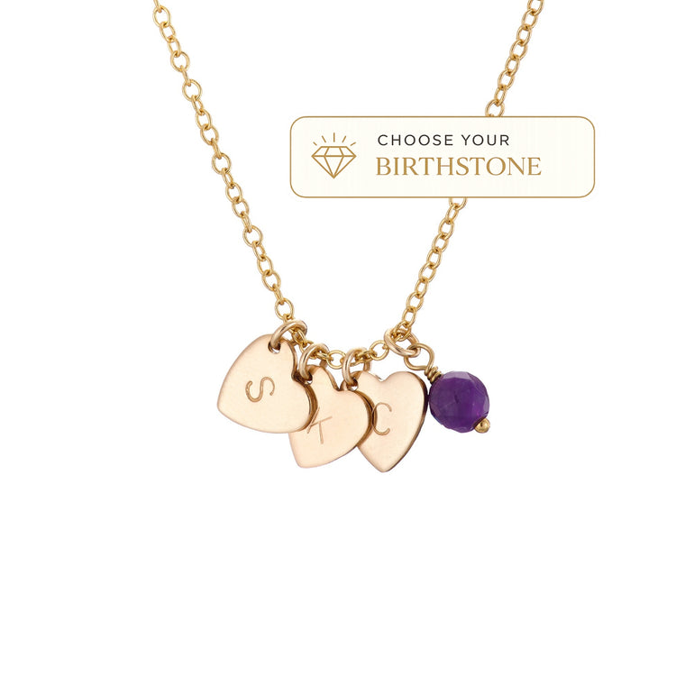 A gold chain necklace with three engraved heart charms and an amethyst birthstone shown on a white background with a 'Choose Your Birthstone' label.