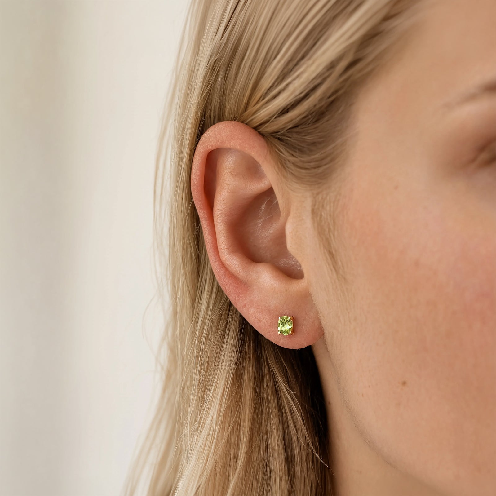 gold peridot birthstone stud in a models ear