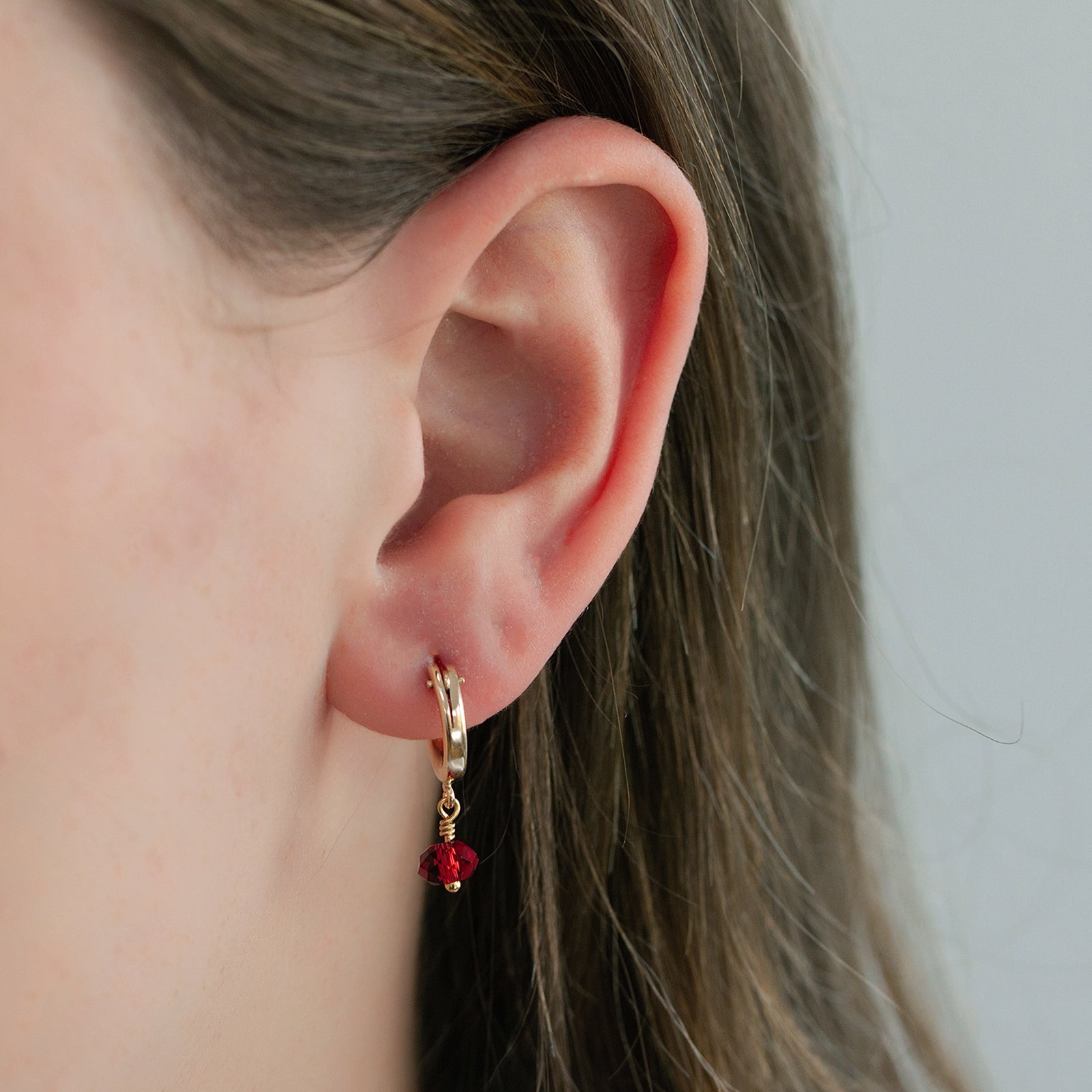 january birthstone hoop earring in gold close up on a model 