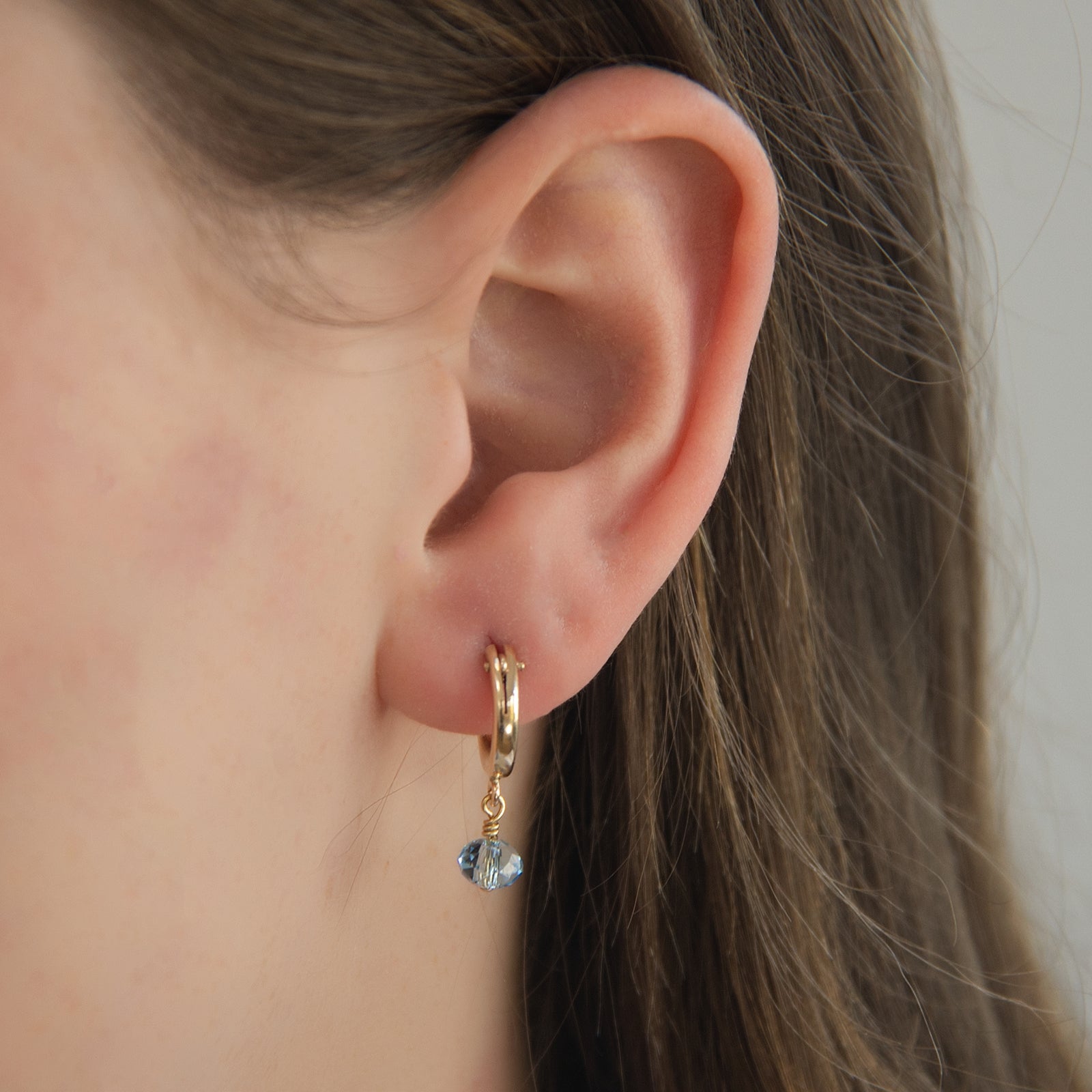 march birthstone hoop earrings on a model close up 