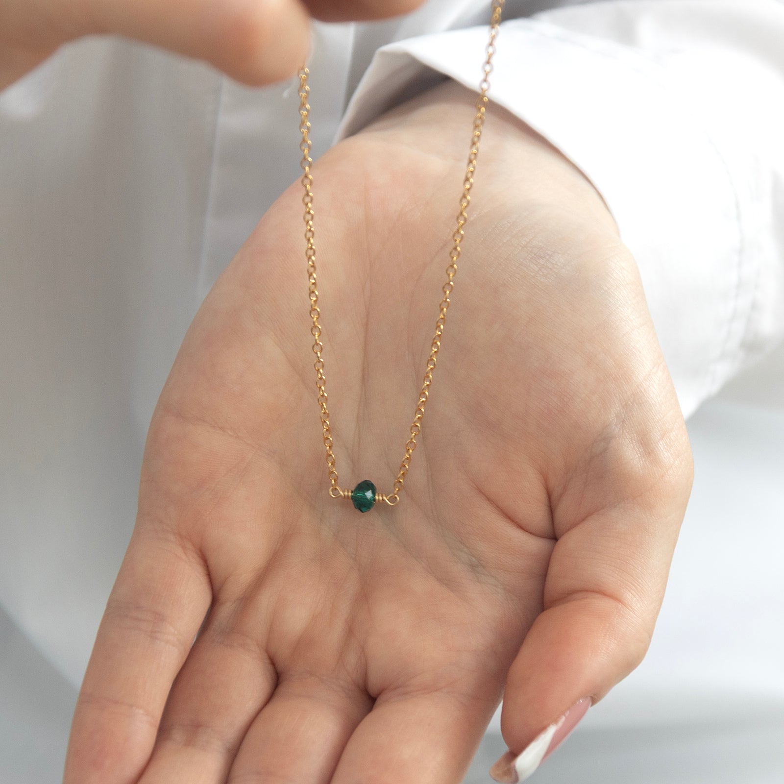 may birthstone necklace gold in a models hand 