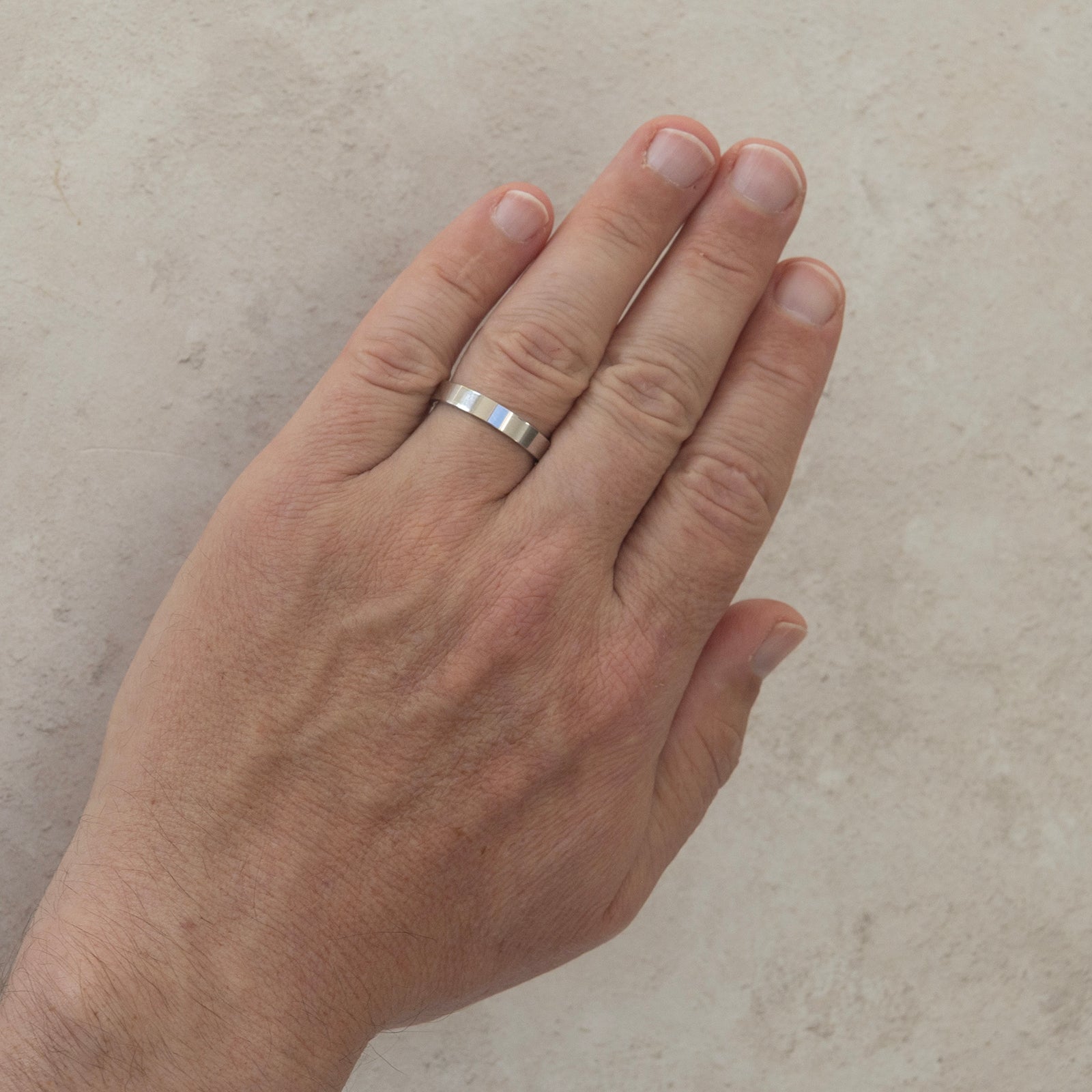 The Always wedding ring worn on a model's hand — a plain 4mm men's ring with a flat outer surface and polished finish