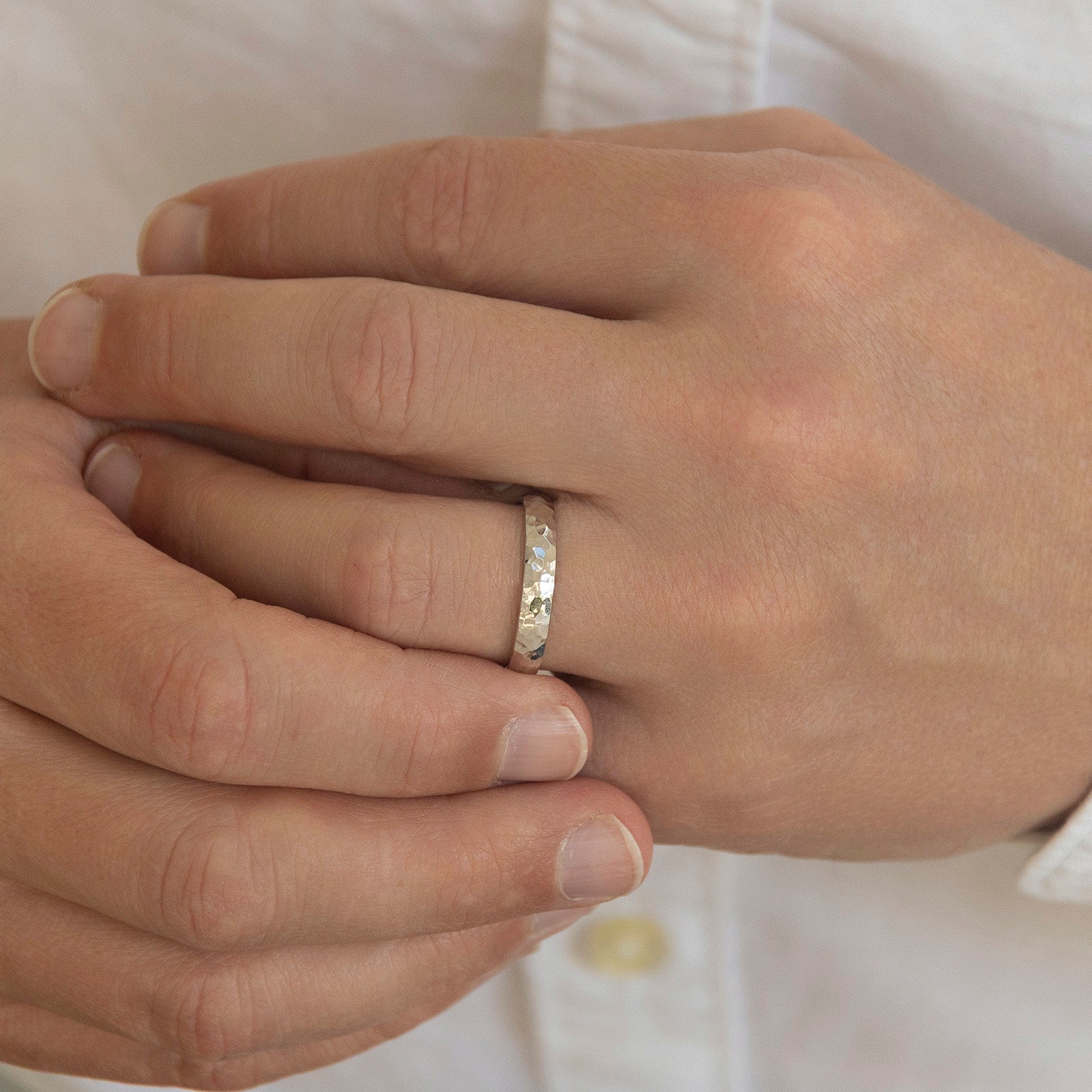 The Anchor wedding ring worn on a model's hand — a 4mm men's ring with a hand hammered, polished surface
