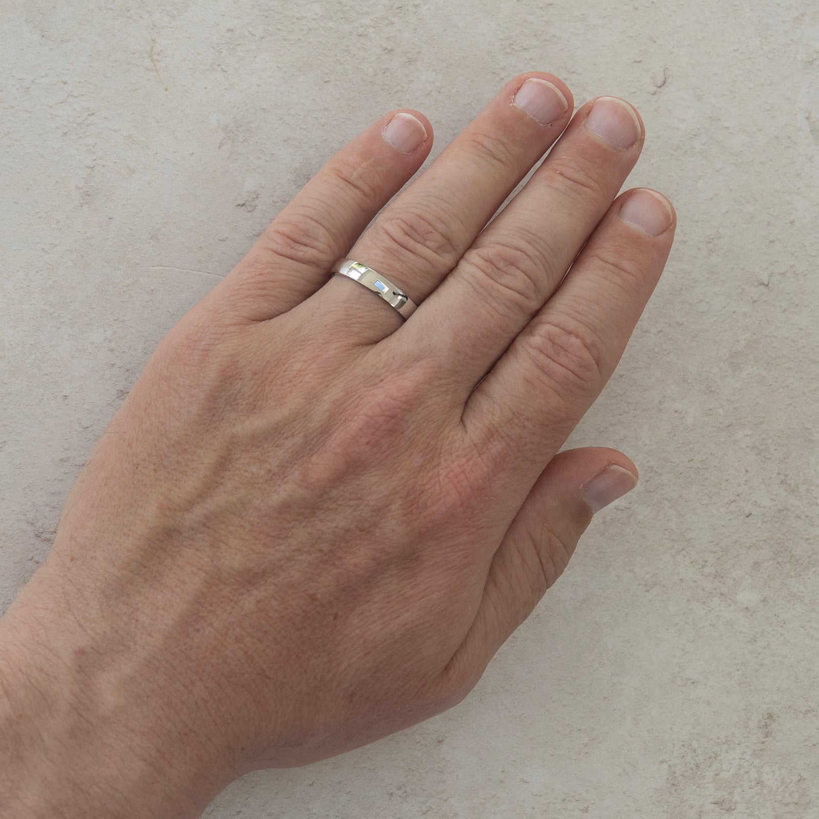 The Hand in Hand wedding ring worn on a model's hand — a plain polished 4mm men's ring