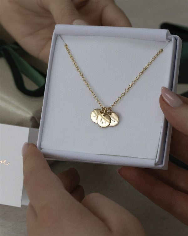 Dainty gold initial necklace with three engraved discs in its open gift box